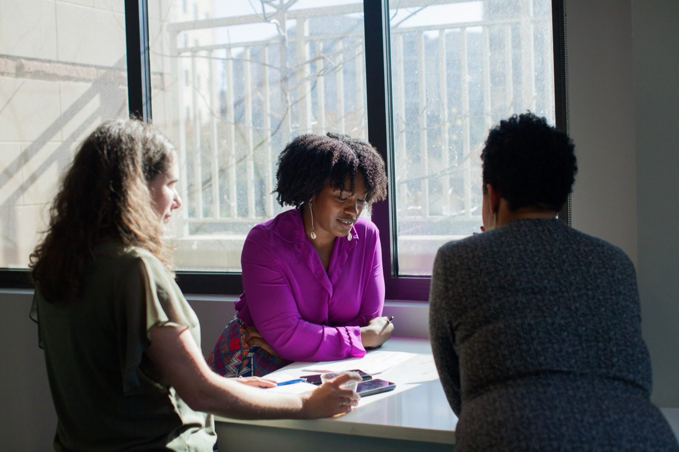 Christina Scott working through a plan with two leaders at a sunlit table